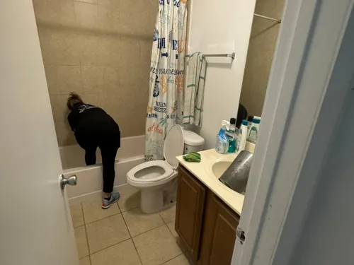 Ire Cleaning Services team member scrubbing a bathtub during a bathroom deep clean