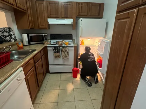 Ire Cleaning Services team member cleaning inside a refrigerator in an apartment kitchen