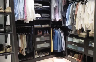 Neatly organized walk-in closet with folded clothes and paired shoes after an Ire Cleaning Services cleanout