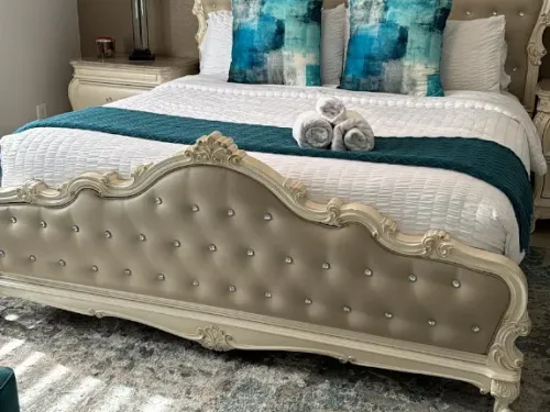 Staged Airbnb bedroom with hotel-style rolled towels on the bed