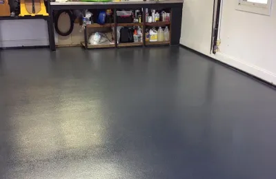 Clean epoxy-coated garage floor with organized workbench after an Ire Cleaning Services garage cleaning
