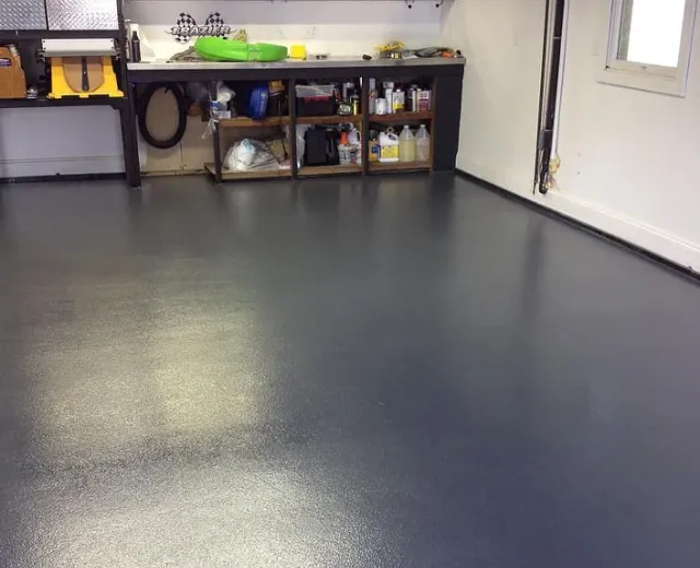 Clean epoxy-coated garage floor with organized workbench after an Ire Cleaning Services garage cleaning