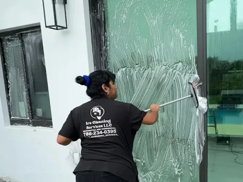 Ire Cleaning Services team member squeegeeing a glass sliding door on a pool patio